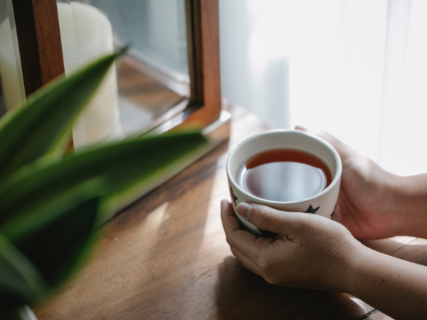 A woman's hands cradle a mug of warm tea.