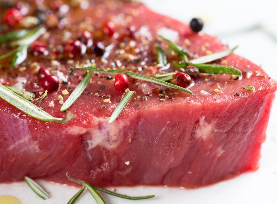 Steak marinating in herbs, spices and oil.