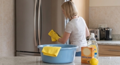A woman wipes the exterior of a fridge